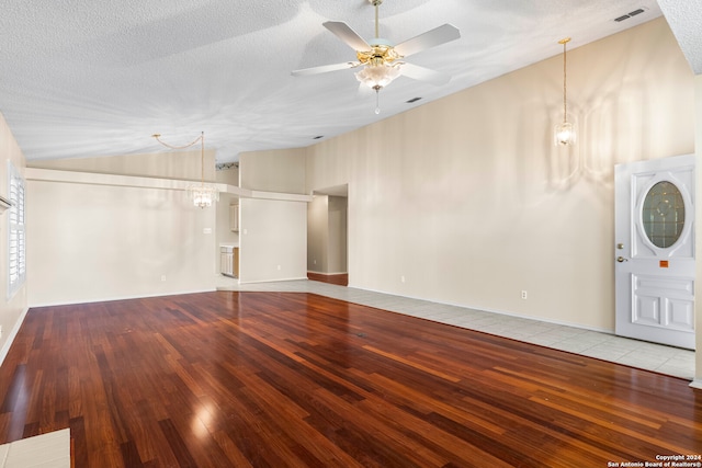 unfurnished living room with a textured ceiling, high vaulted ceiling, wood-type flooring, and ceiling fan with notable chandelier