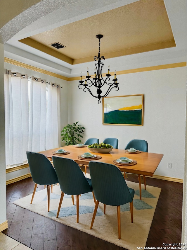 dining space with a textured ceiling, a tray ceiling, a chandelier, and wood-type flooring