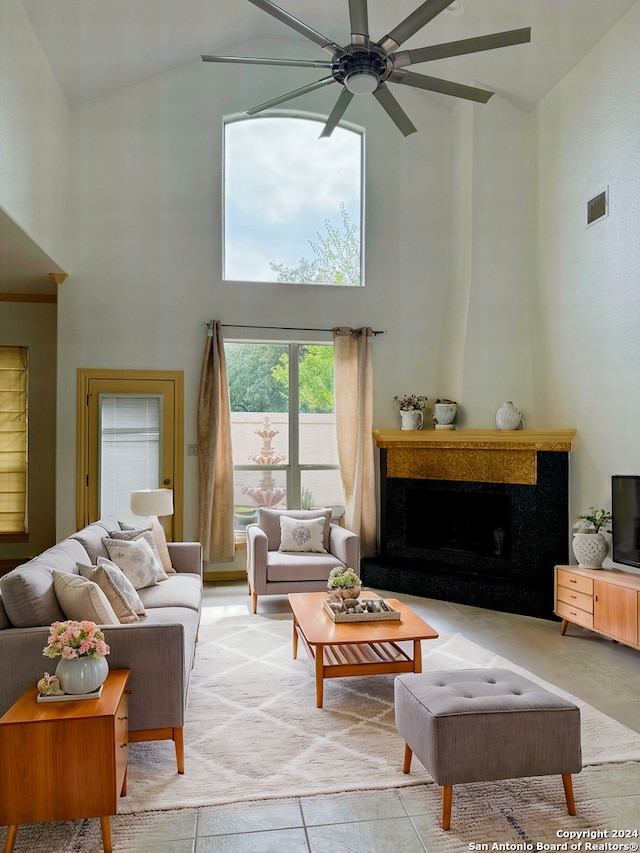 living room with a high end fireplace, high vaulted ceiling, and ceiling fan