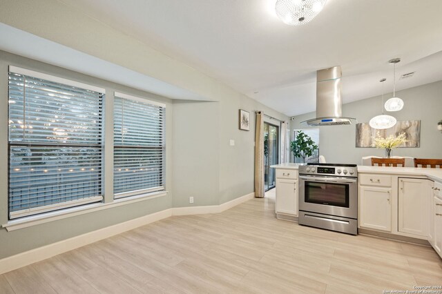 kitchen featuring stainless steel electric stove, island exhaust hood, white cabinetry, light hardwood / wood-style flooring, and pendant lighting