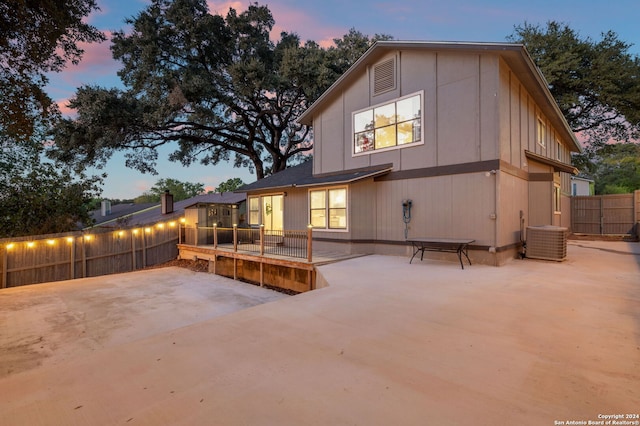 back house at dusk with a patio area and central AC unit