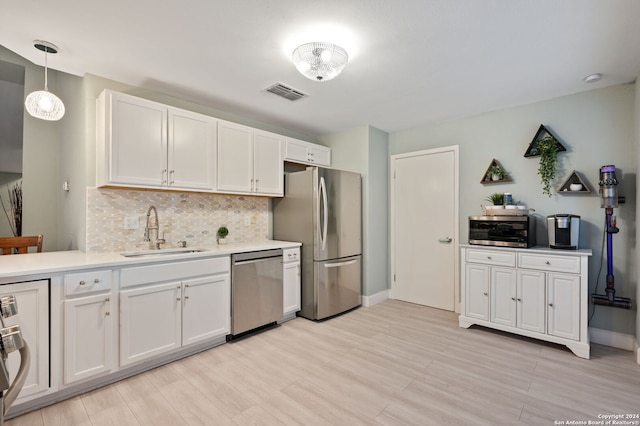 kitchen featuring sink, white cabinets, pendant lighting, appliances with stainless steel finishes, and light hardwood / wood-style floors