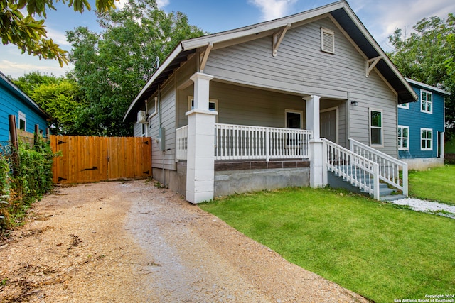 bungalow-style home featuring covered porch and a front lawn