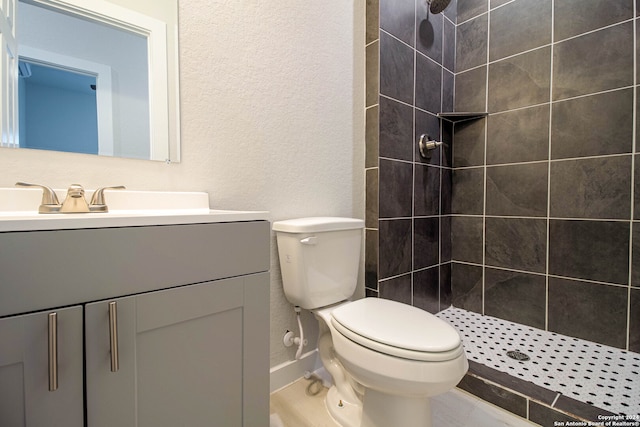 bathroom featuring toilet, vanity, tile patterned floors, and tiled shower