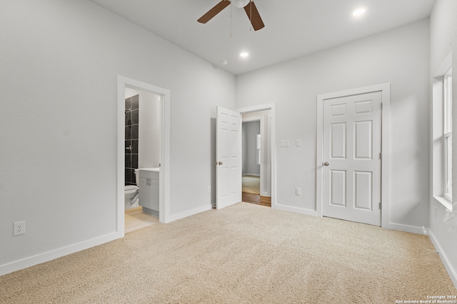 unfurnished bedroom featuring connected bathroom, light colored carpet, a closet, and ceiling fan