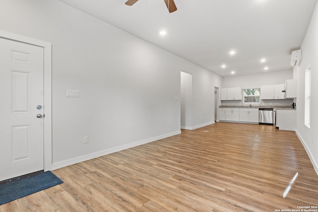 unfurnished living room with an AC wall unit, light hardwood / wood-style floors, and ceiling fan