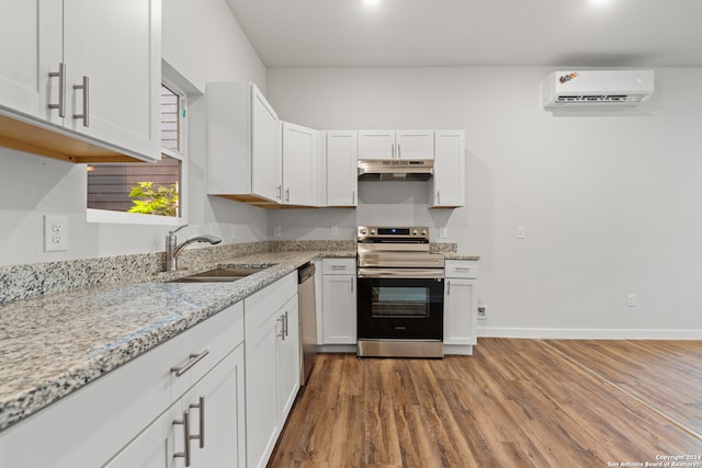 kitchen featuring stainless steel appliances, sink, a wall unit AC, and white cabinets