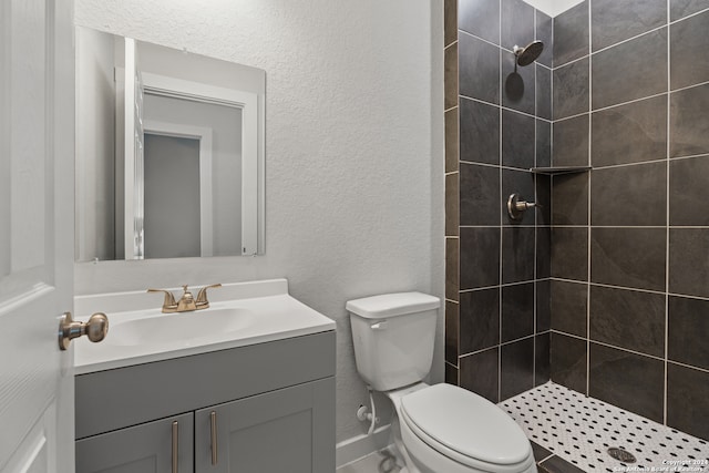 bathroom with vanity, tiled shower, and toilet