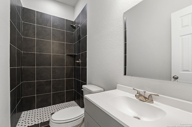 bathroom with toilet, vanity, and tiled shower