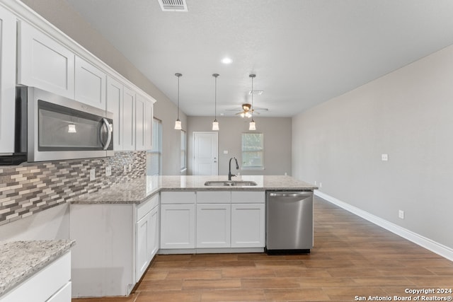 kitchen with kitchen peninsula, white cabinetry, wood-type flooring, sink, and stainless steel appliances