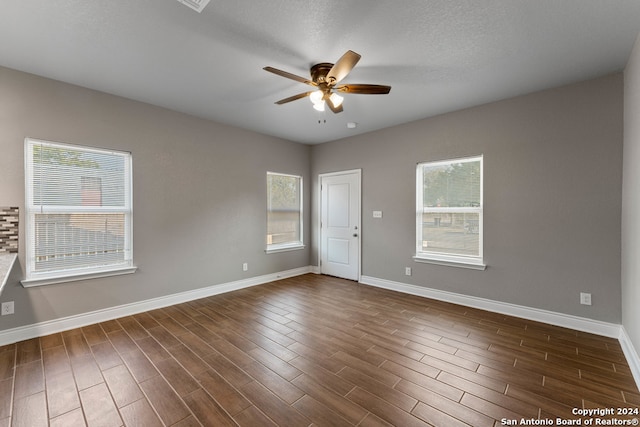 unfurnished room with dark wood-type flooring, ceiling fan, a textured ceiling, and a wealth of natural light