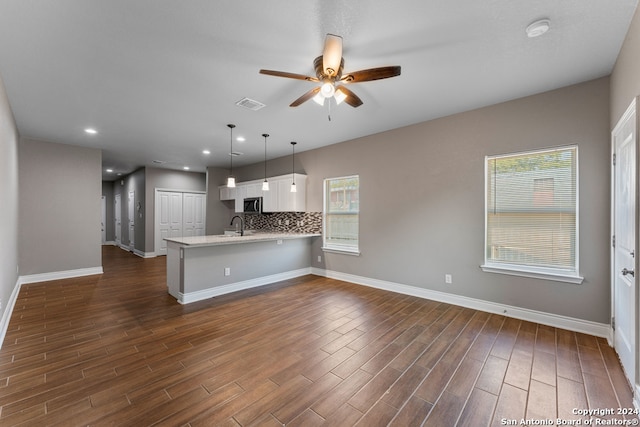 kitchen featuring kitchen peninsula, white cabinets, hanging light fixtures, backsplash, and dark hardwood / wood-style floors