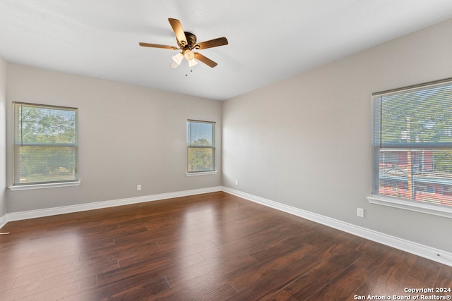 spare room featuring a wealth of natural light, dark wood-type flooring, and ceiling fan