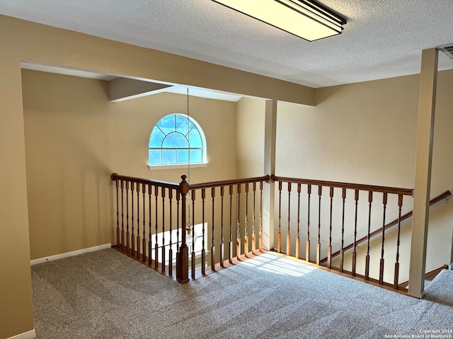 hallway featuring carpet floors and a textured ceiling