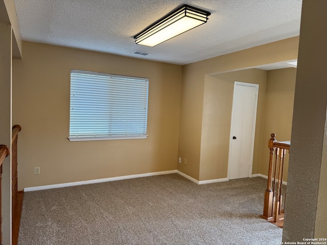 carpeted empty room with a textured ceiling