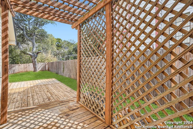 deck featuring a pergola and a lawn