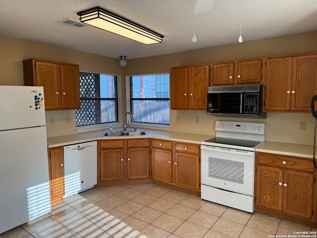 kitchen featuring white appliances, light tile patterned flooring, a textured ceiling, and sink