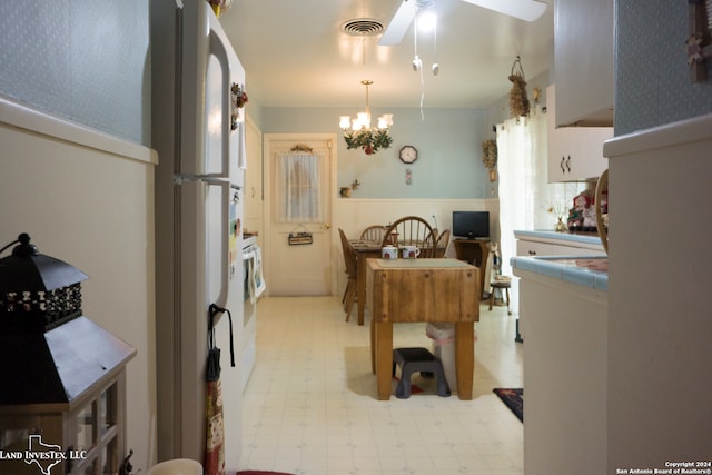 kitchen featuring decorative light fixtures, white fridge, tile counters, and ceiling fan with notable chandelier