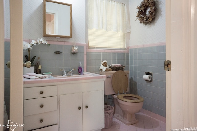 bathroom with vanity, toilet, tile walls, and tile patterned flooring