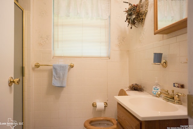 bathroom with vanity, walk in shower, toilet, and tile walls