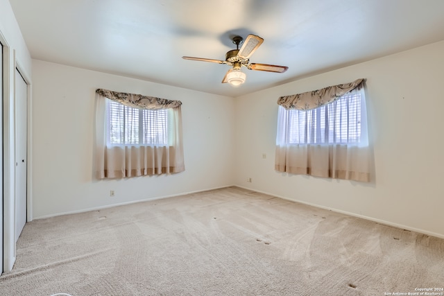 empty room with light carpet, a healthy amount of sunlight, and ceiling fan