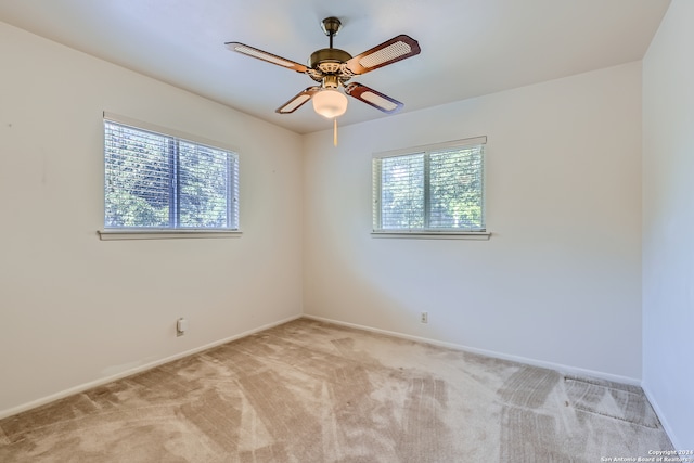 carpeted empty room featuring ceiling fan and plenty of natural light