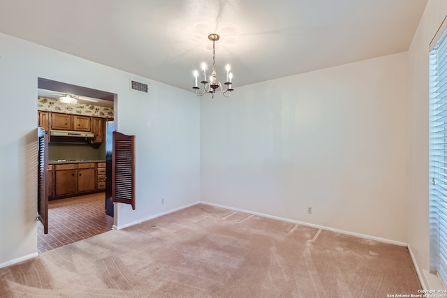 unfurnished room featuring a notable chandelier and carpet flooring