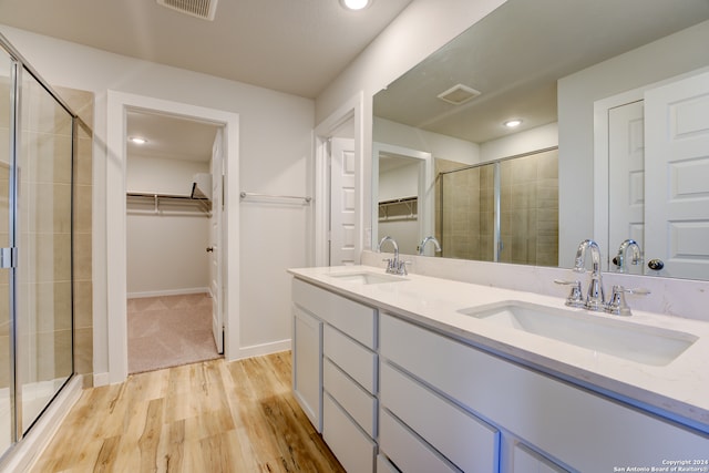 bathroom with hardwood / wood-style floors, vanity, and a shower with door