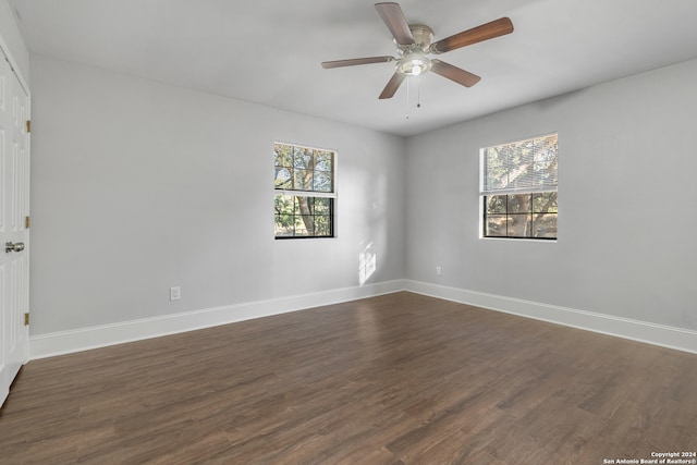 empty room featuring a wealth of natural light, dark hardwood / wood-style floors, and ceiling fan