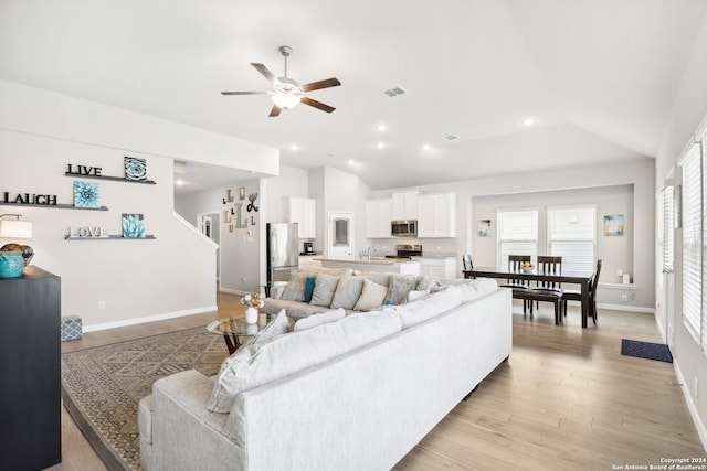 living room with light hardwood / wood-style floors, sink, vaulted ceiling, and ceiling fan