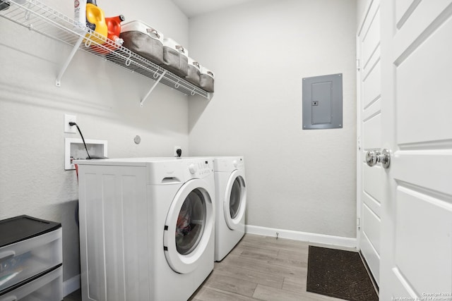 laundry room with electric panel, washing machine and dryer, and light hardwood / wood-style floors