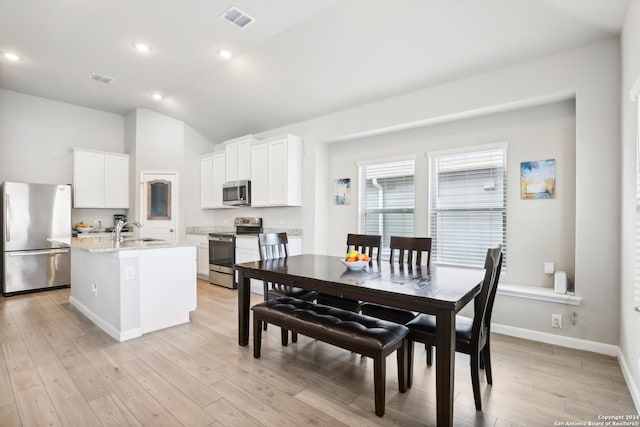 kitchen featuring light hardwood / wood-style floors, appliances with stainless steel finishes, white cabinets, and an island with sink