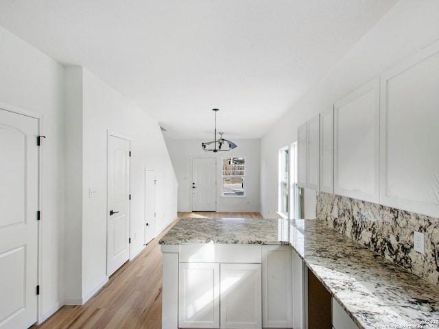 kitchen with light hardwood / wood-style floors, white cabinetry, a chandelier, and hanging light fixtures