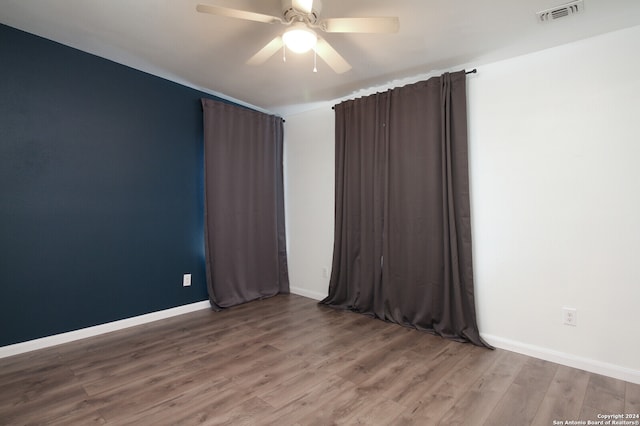 empty room with hardwood / wood-style flooring and ceiling fan