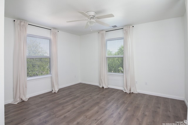 empty room featuring dark wood-type flooring, ceiling fan, and a healthy amount of sunlight