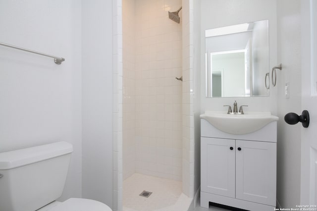 bathroom featuring vanity, toilet, and a tile shower