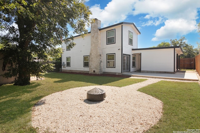 back of property featuring a patio area, an outdoor fire pit, and a lawn