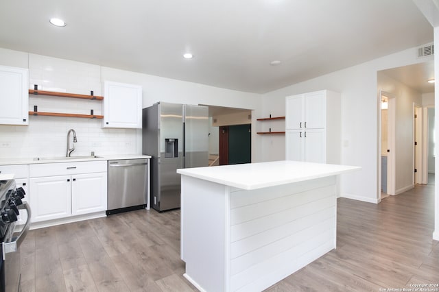 kitchen with backsplash, appliances with stainless steel finishes, light wood-type flooring, and white cabinetry