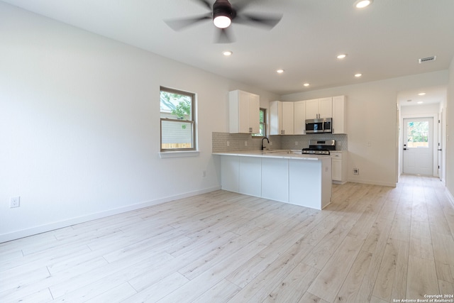 kitchen with plenty of natural light, stainless steel appliances, kitchen peninsula, and white cabinets