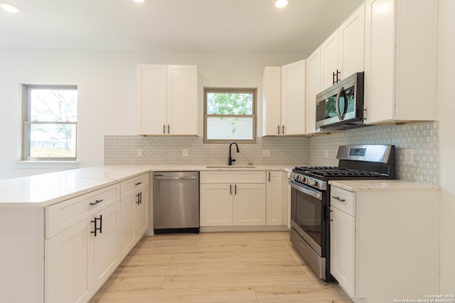 kitchen featuring sink, appliances with stainless steel finishes, kitchen peninsula, and white cabinets