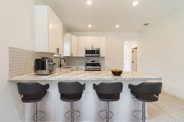 kitchen with light hardwood / wood-style floors, stainless steel appliances, sink, and kitchen peninsula