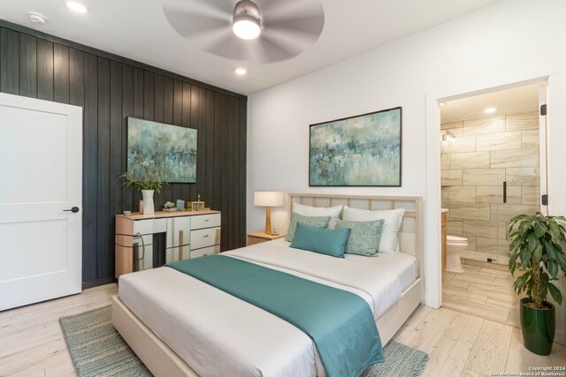 bedroom with ensuite bathroom, light wood-type flooring, wooden walls, and ceiling fan