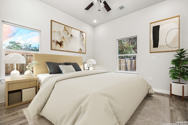 bedroom featuring multiple windows, hardwood / wood-style flooring, and ceiling fan