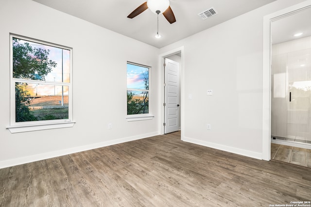 unfurnished bedroom with ensuite bath, wood-type flooring, and ceiling fan