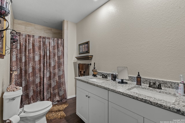 bathroom featuring a textured ceiling, hardwood / wood-style flooring, toilet, vanity, and curtained shower