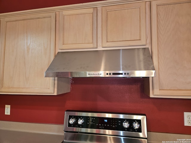 kitchen featuring light brown cabinetry, stainless steel range, and extractor fan