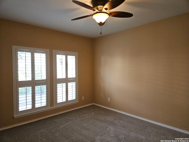 spare room featuring dark carpet and ceiling fan