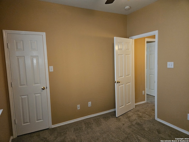 unfurnished bedroom featuring dark colored carpet and ceiling fan