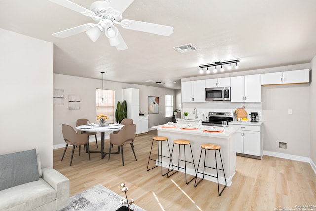 kitchen with white cabinetry, decorative light fixtures, a breakfast bar area, a kitchen island, and appliances with stainless steel finishes