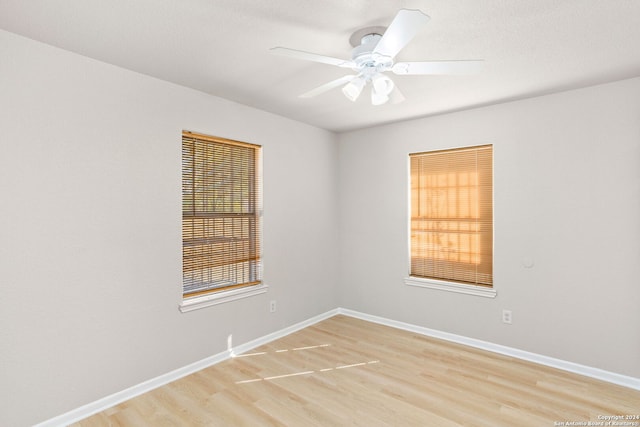 empty room featuring ceiling fan, a healthy amount of sunlight, and light hardwood / wood-style floors